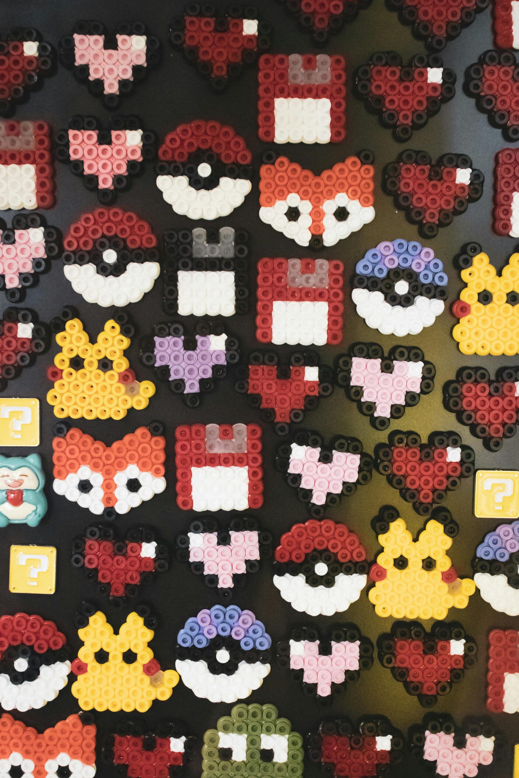 A vibrant display of bead art showcasing popular symbols like pixelated hearts and gaming icons.